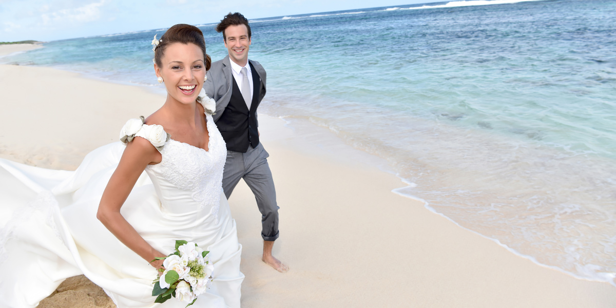 Couple walking along shoreline in wedding attire