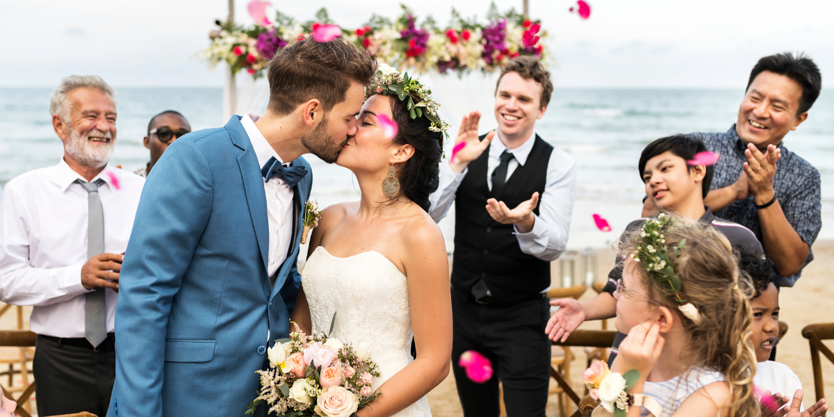 Newly married couple kissing at ceremony on beach