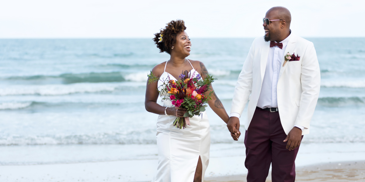 Couple on beach dressed in wedding attire